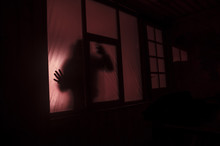 Horror Concept. The Silhouette Of A Human With Sprayed Arms In Front Of A Window. At Night.