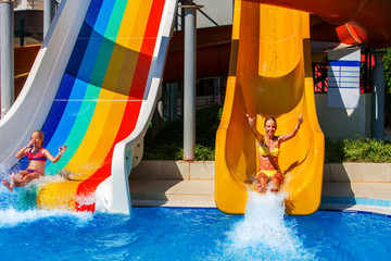 Wall Mural - Swimming pool slides for children on water slide at aquapark and thumb up. Summer holiday. There are two kids in aqua park. Outdoor.