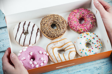 hands holding assorted donuts stuffed in a box