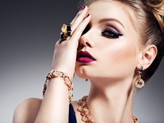 Pretty girl with beautiful face bright make-up  and gold jewelry