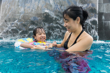 Wall Mural - Asian Chinese mother and daugther playing at swimming pool