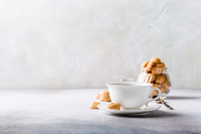 White Cup Of Coffee With Amaretti Cookies On Light Gray Background With Copy Space.