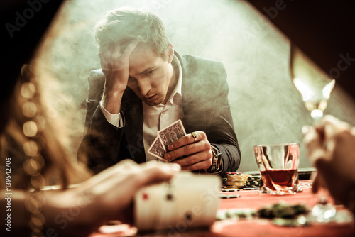 фотография portrait of upset man looking at poker cards in hand