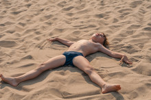 Boy Lying On The Beach Apart Arms And Legs