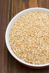 Sticker - raw rice in red bowl on wooden background