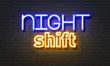 Night shift neon sign on brick wall background.