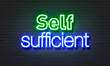 Self sufficient neon sign on brick wall background.