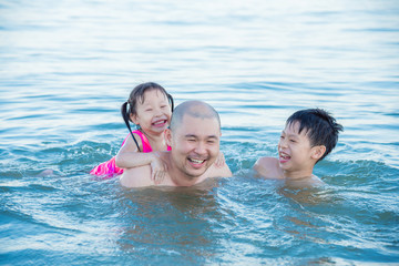 Wall Mural - Asian father and his children happy in the sea