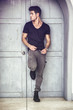 © theartofphoto - Handsome young man outdoors in front of old house's wood entrance door, looking away to a side
