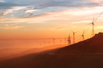 wind turbines during sunset with andalusian hills, atlantic ocean and mountain of africa on backgrou