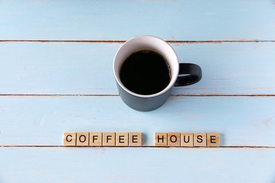 COFFEE HOUSE block letters and cup black coffee on the old vintage table.