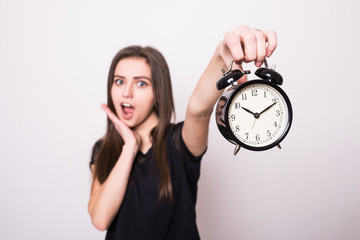 Happy woman holding clock against a grey