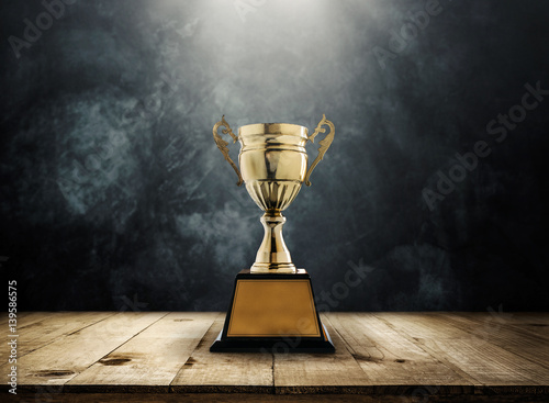 Fotografía champion golden trophy placed on wooden table with dark background copy space ready for your design