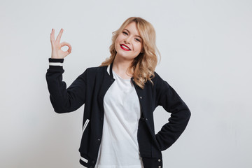 Smiling cheerful girl in casual clothes showing okay sign