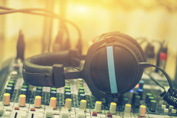 Dj equipment in a studio working with sound and light mixer console,sound mixer with headphones resting on the top,boutique recording studio control desk,selective focus,vintage color