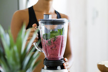 Woman Blending Spinach, Berries, Bananas And Almond Milk To Make A Healthy Green Smoothie