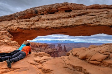 Friends enjoying the view of canyon and mountains. Mesa Arch. Canyonlands National Park. Moab. Utah. United States.