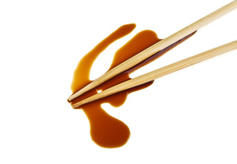 Splashes of soy sauce and chopsticks isolated on white background