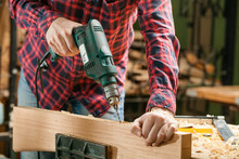 Man Drills The Wooden Plank