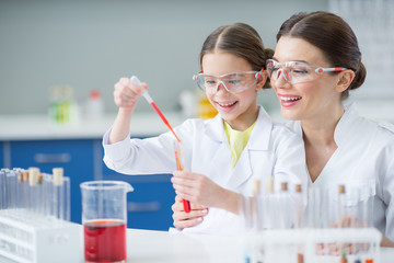 portrait of smiling woman teacher and girl student scientists making experiment in lab