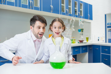 Wall Mural - portrait of exited man teacher and girl student scientists making experiment in lab