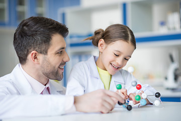 Wall Mural - Smiling teacher and student scientists looking at molecule model in lab