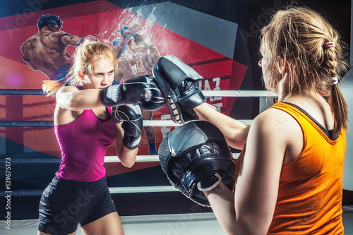 Plakat Młoda dorosła kobieta robi bokserskiemu szkoleniu z jej trenerem