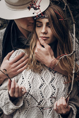 Wall Mural - Sensual romantic man in cowboy hat hugging a beautiful gypsy brunette woman from behind, while she is holding a berry tree branch closeup