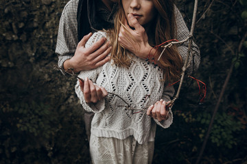 Wall Mural - stylish hipster couple tender hugging. boho gypsy woman holding branch and man in hat embracing her. atmospheric sensual moment. rustic fashionable look.