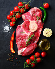 Wall Mural - Raw meat, beef steak on a stone cutting board with rosemary, spices, salt, oil, cherry tomatoes, hot pepper and herbs