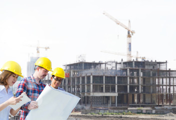 Engineer group and worker meeting, discussion with construction blueprint on site work background