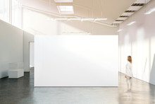 Woman Walking Near Blank White Wall Mockup In Modern Gallery. Girl Admires A Clear Big Stand Mock Up In Museum With Contemporary Art Exhibitions. Large Hall Interior, Banner Exposition Show