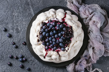 Homemade Meringue Cake Pavlova With Whipped Cream, Fresh Blueberries And Blueberry Sauce On Vintage Cake Stand On Black Concrete Texture Background. Top View, Space