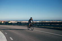 A Cyclist Rides In The Middle Of The Road Overlooking Barcelona Skyline