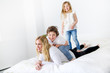 © Louis-Photo - Portrait of a happy mother and her children lying on a bed