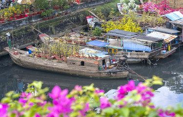 Wall Mural - Ho Chi Minh City, Vietnam - January 26, 2017: Flowers boats at flower market on along canal wharf. This is place where farmers sell apricot blossom and other flowers on Lunar New Year in Vietnam