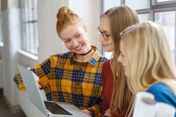 frauen schauen auf laptop und unterhalten sich
