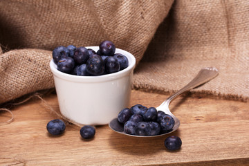 Wall Mural - Pot of blueberries with spoon on a rustic background