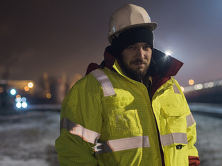 Wall Mural - Portrait of young construction worker in helmet at night.