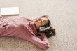 © Westend61 - Woman lying on carpet wearing headphones