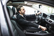 transport, business trip, destination and people concept - close up of young man in suit driving car look on road