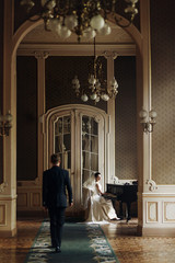 Wall Mural - elegant stylish handsome groom hugging his gorgeous bride while playing the piano. unusual luxury wedding couple in retro style