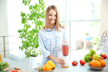 Wall Mural - Young beautiful woman making fresh juice in kitchen