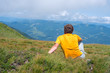 © sanechka - Traveler sitting on an alpine meadow, among lush grass