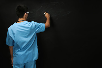 Wall Mural - Young handsome medical student on blackboard background