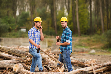 Wall Mural - Two guys, with yellow helmets on their heads, rest in the forest after work and drink beer