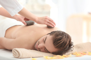 Canvas Print - Young man having stones massage in spa salon