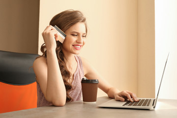 Sticker - Young woman shopping online with credit card and laptop at home