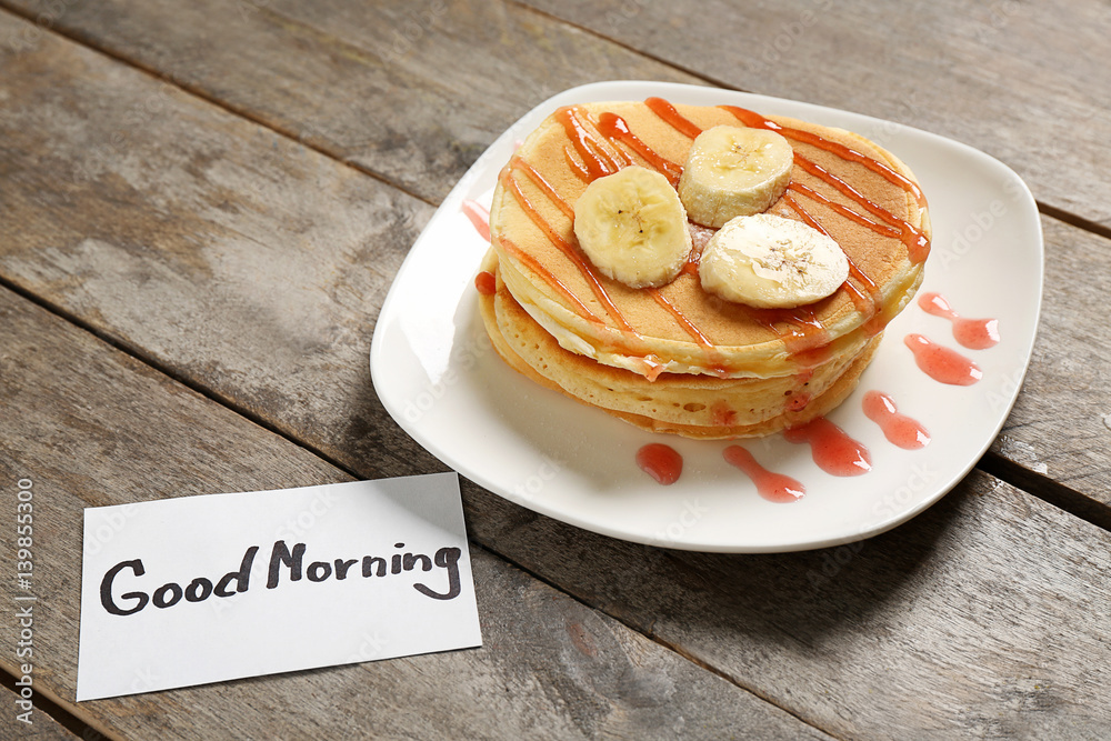 Delicious breakfast and GOOD MORNING greeting note on wooden table closeup