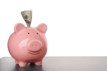 Poster - Pink ceramic piggy bank with banknote on wooden table